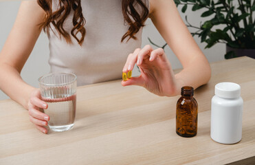 A woman holds omega-3 fish oil capsules. Healthy lifestyle, prevention and treatment of diseases. The woman takes and drinks dietary supplements and vitamins for skin, nails and hair. 