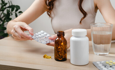 A woman holds omega-3 fish oil capsules. Healthy lifestyle, prevention and treatment of diseases. The woman takes and drinks dietary supplements and vitamins for skin, nails and hair. 
