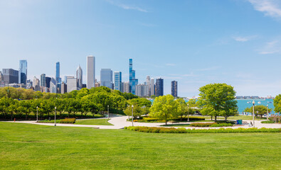 Sunny view of downtown Chicago with iconic skyscrapers rising above a lush green park meadow