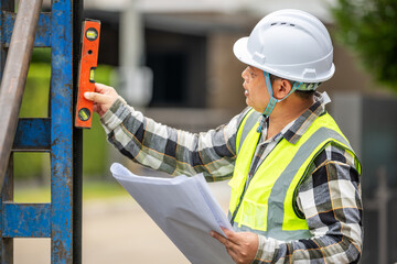 Construction Worker Using Leveling Tool and Blueprint at Construction Site Wea Safety Helmet and High Visibility Vest Du Building Project