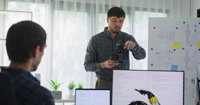 Team adult male engineer develop present AI robotics hand project at tech workspace. Artificial intelligence, collaboration support prototype development, robotic, debugging, machine learn, training.