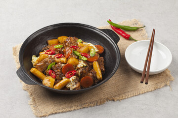  Jjimdak is a dish made by simmering chicken pieces with carrots, potatoes, garlic, peppers, green onions, onions, and glass noodles, and seasoning it with soy sauce or red pepper paste.