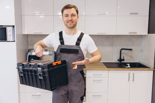 Plumber Holding Toolbox and Gesturing in Kitchen