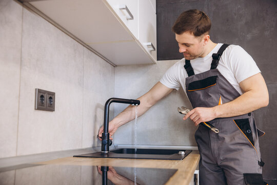 Plumber checking water flow after installing kitchen faucet