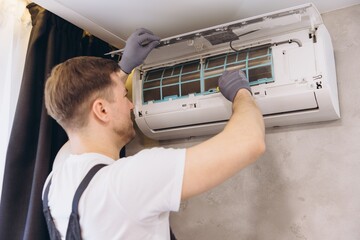 Professional plumber repairing modern air conditioner unit