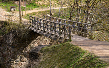 Old wooden bridge with iron locks on the railings, early spring.