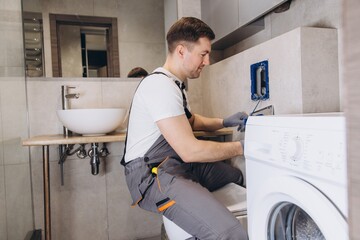 Plumber Installing Washing Machine in Modern Bathroom