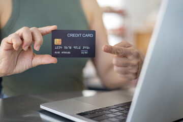 Close-up of woman holding credit card and using tablet sitting at coffee shop
