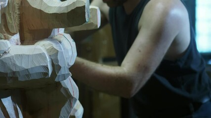 Slow Motion close-up of craftsman hands skillfully uses chisel to carve detailed wooden Madonna and bambino Gesu statue, highlighting the precision, artistry, and care in traditional sculpture making