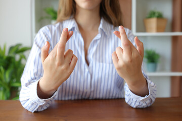 Woman hands crossing fingers in a house