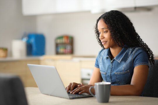 Black woman in a kitchen using laptop