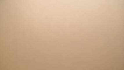 Subtle light beige background surface with uniform texture, small imperfections and minimalist composition for clean neutral overlay.