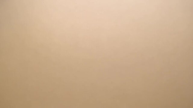 Subtle light beige background surface with uniform texture, small imperfections and minimalist composition for clean neutral overlay.