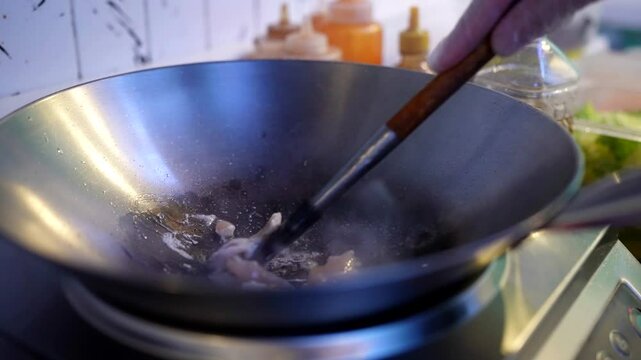 Chicken cooking in a heated wok, oil sizzling around tender chunks of raw meat, ready for stir-fry.