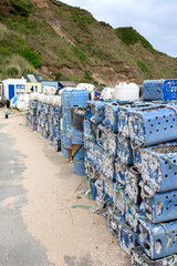 Lobster and crab commercial fishing pots traps stacked  at a harbour port background backdrop. Made from recycled plastic containers.
