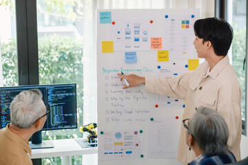 senior programmer bootcamlp,Asian young instructor guides senior learners through a programming on...