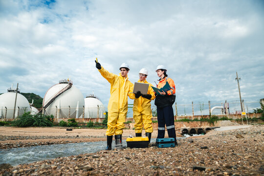 Factory Worker in Hazmat Suit Collecting Oil and Water Samples from Industrial Beach for Toxic Pollution Survey