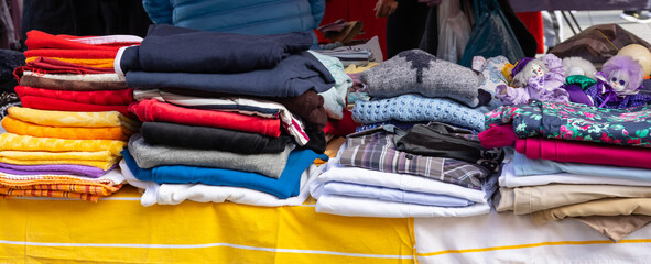 A variety of old worn clothes jumpers and blankets offered on a flea market