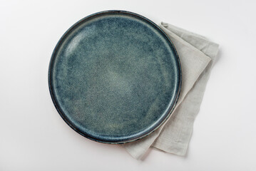 An empty grey textured plate with a napkin on a white table