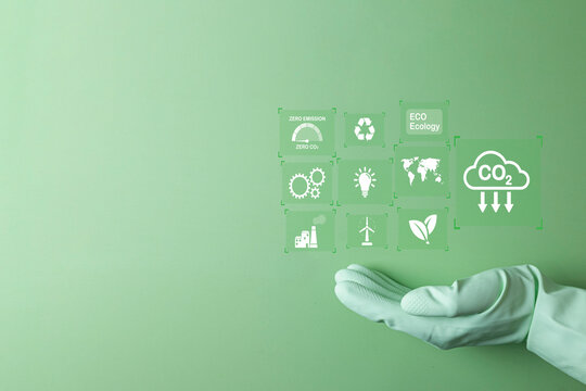 A virtual dashboard with green technology icon and CO2 reduction goals held by a hand. Represents ESG(environmental, social, governance,),CO2 emission reduction,green energy,climate action,net-zero.