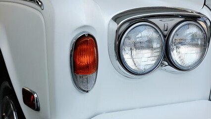 Headlights Of White Vintage Car Close Up View In Soft Sepia Light. Classic Round Lamps On Retro Vehicle Captured In Detailed Artistic Composition.