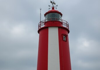 Red and white lighthouse against a cloudy sky, featuring a weather vane