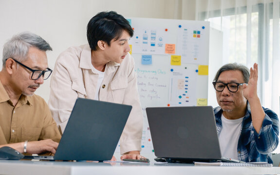 Asian senior bootcamp team asking and  learning programming with software training and whiteboard collaboration