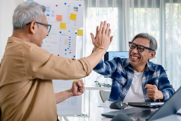 Senior developer team celebrates success in software collaboration and coding at a modern computer workstation