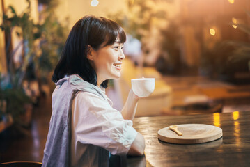 暖かい雰囲気の空間で、コーヒーを飲む若い女性