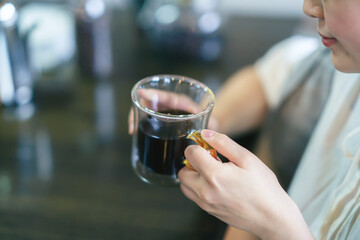 暖かい雰囲気の空間で、コーヒーを飲む若い女性
