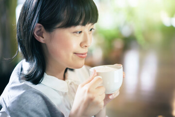 暖かい雰囲気の空間で、コーヒーを飲む若い女性