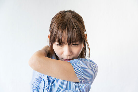口をひじに当ててせきをする女性