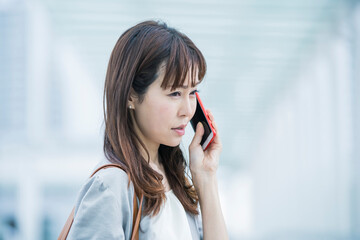 困った表情で電話するビジネスウーマン