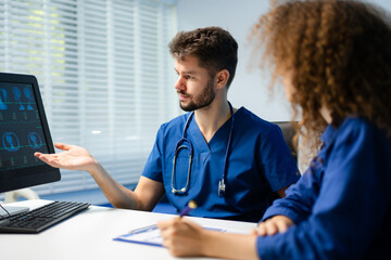 Male doctor explains health scan results to female patient using a computer screen. Concept of diagnosis, health tech, medical consultation