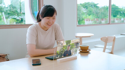 A smiling woman on a video call using a futuristic transparent tablet, embracing the remote work and digital nomad lifestyle.