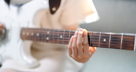 Focus hand of woman on playing electric guitar chord music