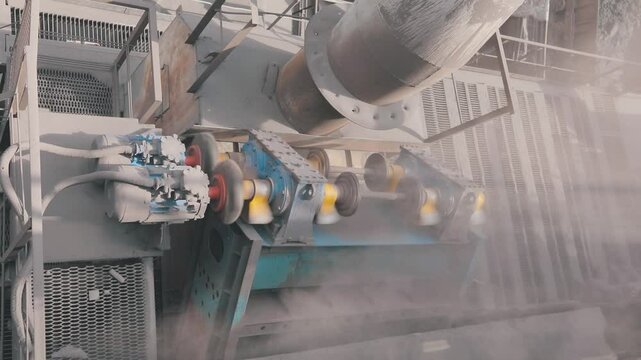 Ore crushing by crushing machine in sintering plant. The crushing machine crushes the ore, close-up. Mechanical processing and crushing of iron ore in sintering plant.