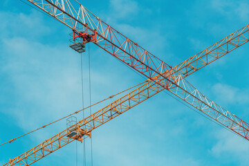Construction cranes lifting heavy load on construction site
