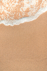 Top view of wet sand and sea foam at ocean shoreline, natural seaside background
