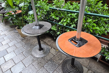 Urban Outdoor Cafe Setting with Empty Tables and Greenery on Stone Pavement