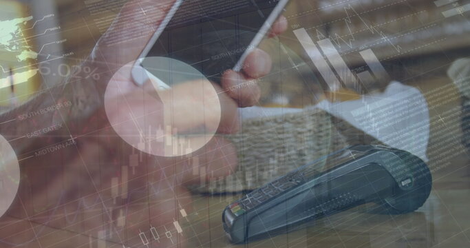 Image of statistics and financial data processing over caucasian man paying with smartphone