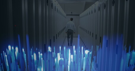Image of glowing blue light trails over rear view of male engineer walking in server room
