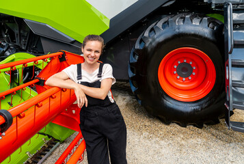 Portrait of female agricultural worker leaning on combine harvester header