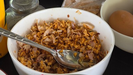 Golden brown crispy fried garlic served in a white bowl, commonly used as a flavorful topping in Asian dishes.