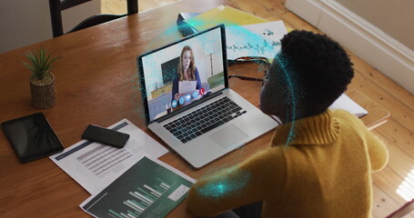 Image of spinning globe over african american woman having a image call on laptop at home