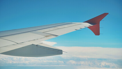 Obraz premium Airplane wing flying above the clouds on a beautiful sunny day