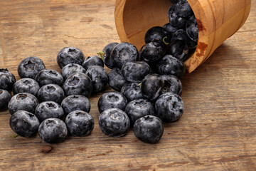 Fresh ripe whole blueberries on rustic wood background mini wooden bucket blue berry