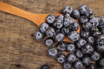 Fresh ripe whole blueberries on rustic wood background wooden spoon blue berry