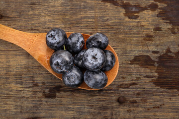 Fresh ripe whole blueberries on rustic wood background wooden spoon blue berry