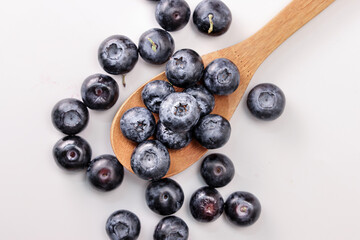 Fresh ripe whole blueberries on white background wooden spoon blue berry 